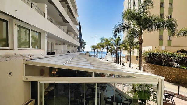 A hotel with a covered outdoor seating area, a pool, and a view of the sea. - Central Two Bedroom Apartment on the Second Line of the Beach in Marbella. (Marbella)