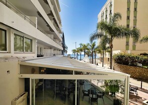A hotel with a covered outdoor seating area, a pool, and a view of the sea. - Central Two Bedroom Apartment on the Second Line of the Beach in Marbella. (Marbella)