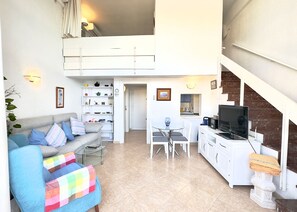 Un grand espace de vie comprenant un canapé, une table à manger et une cuisine à l’arrière-plan.