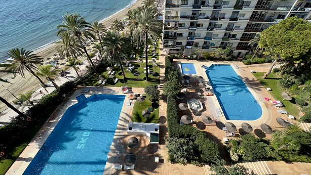 Een resort met twee zwembaden, een strand en uitzicht op de oceaan.