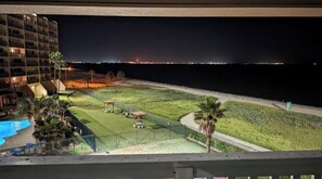 Enjoy a serene beachfront view from this balcony overlooking a pool and gazebo.