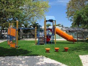 Guests can enjoy a fun playground with a slide and climbing elements on a well-maintained grassy area.