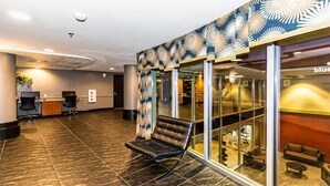 Eine Empfangshalle mit Rezeption, einem Wartebereich mit Stuhl und Glastüren zu einer Lounge.