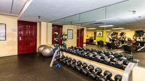 Ein Fitnessraum mit Trainingsgeräten, einer roten Tür und einem Spiegel.