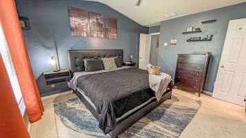 A bedroom with a bed, nightstands, a dresser, a ceiling fan, and a cityscape artwork on the wall.
