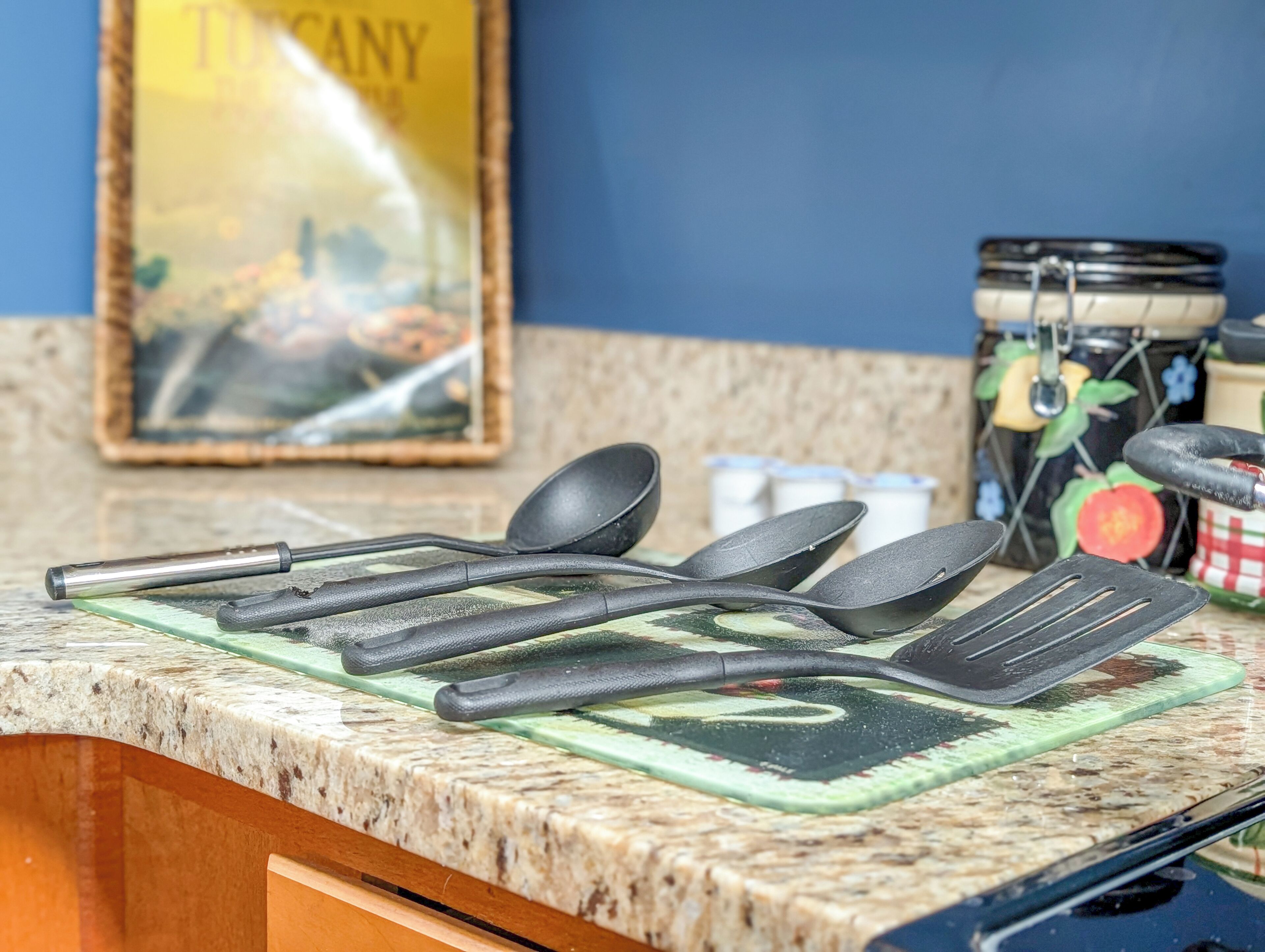 Una encimera de cocina con varios utensilios y un azulejo decorativo.