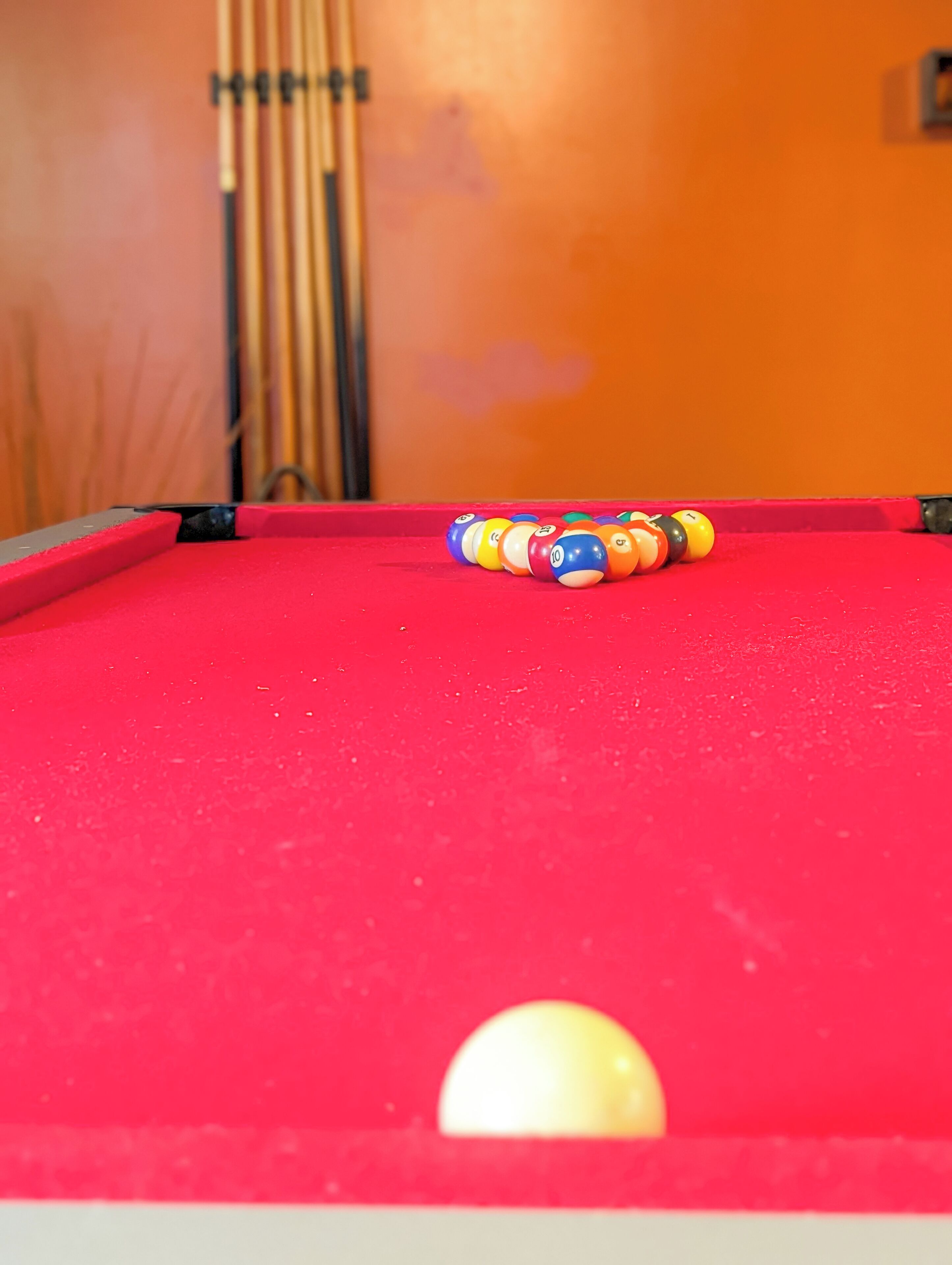 A pool table with a red felt surface and a white cue ball.