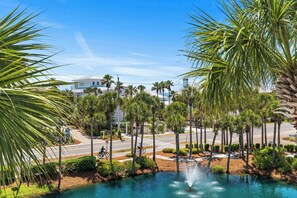 A landscaped area with a fountain, palm trees, and a road with bicycles.