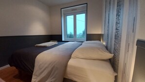 A bedroom with a bed, a window, and a view of greenery outside. - Comfortable house (10 persons), 1,5 km from the sea (Finistère Sud - Bretagne) (Plozévet)