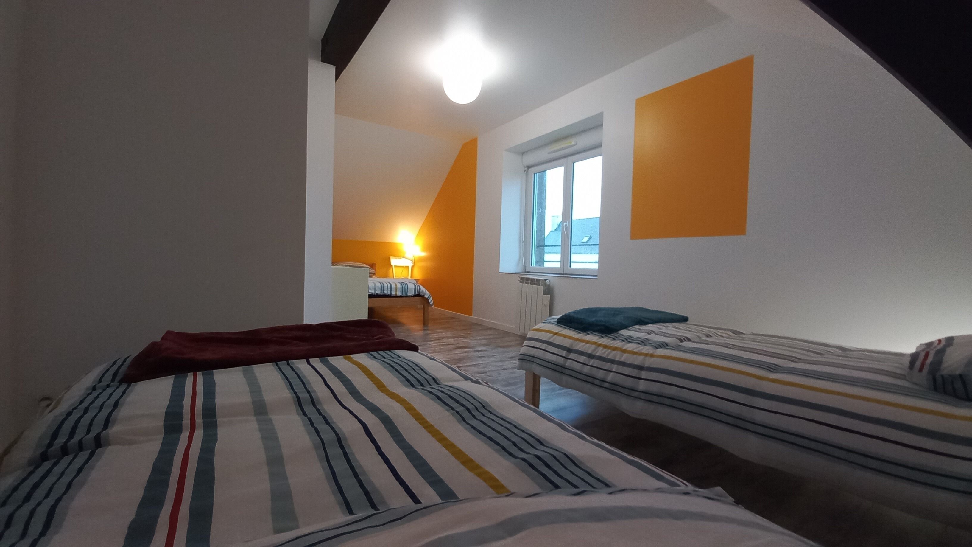 Ein Schlafzimmer mit zwei Betten, einem Fenster und einer Lampe.