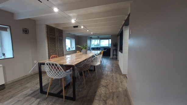 A modern dining area with a long wooden table, white and orange chairs, and a potted plant. - Comfortable house (10 persons), 1,5 km from the sea (Finistère Sud - Bretagne) (Plozévet)