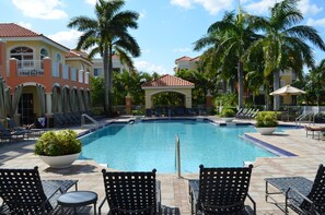 A swimming pool with lounge chairs and palm trees. -  Resort Style Vacation Condo with keyless entry (Palm Beach Gardens)