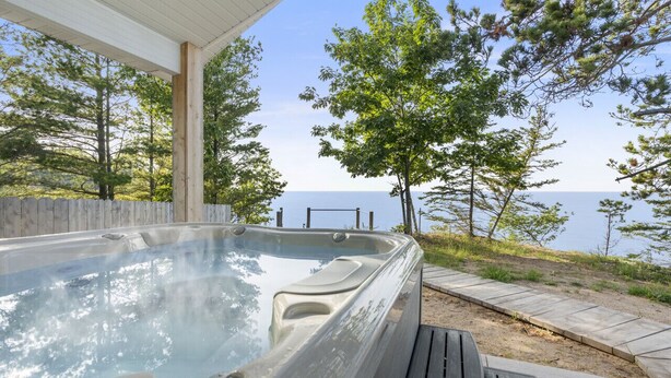 Ein Whirlpool mit Holzterrasse und Blick auf das Wasser.