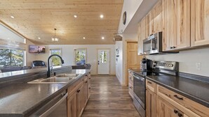 Eine moderne Küche mit Holzschränken, Edelstahlgeräten und einer großen Kochinsel mit Spüle.