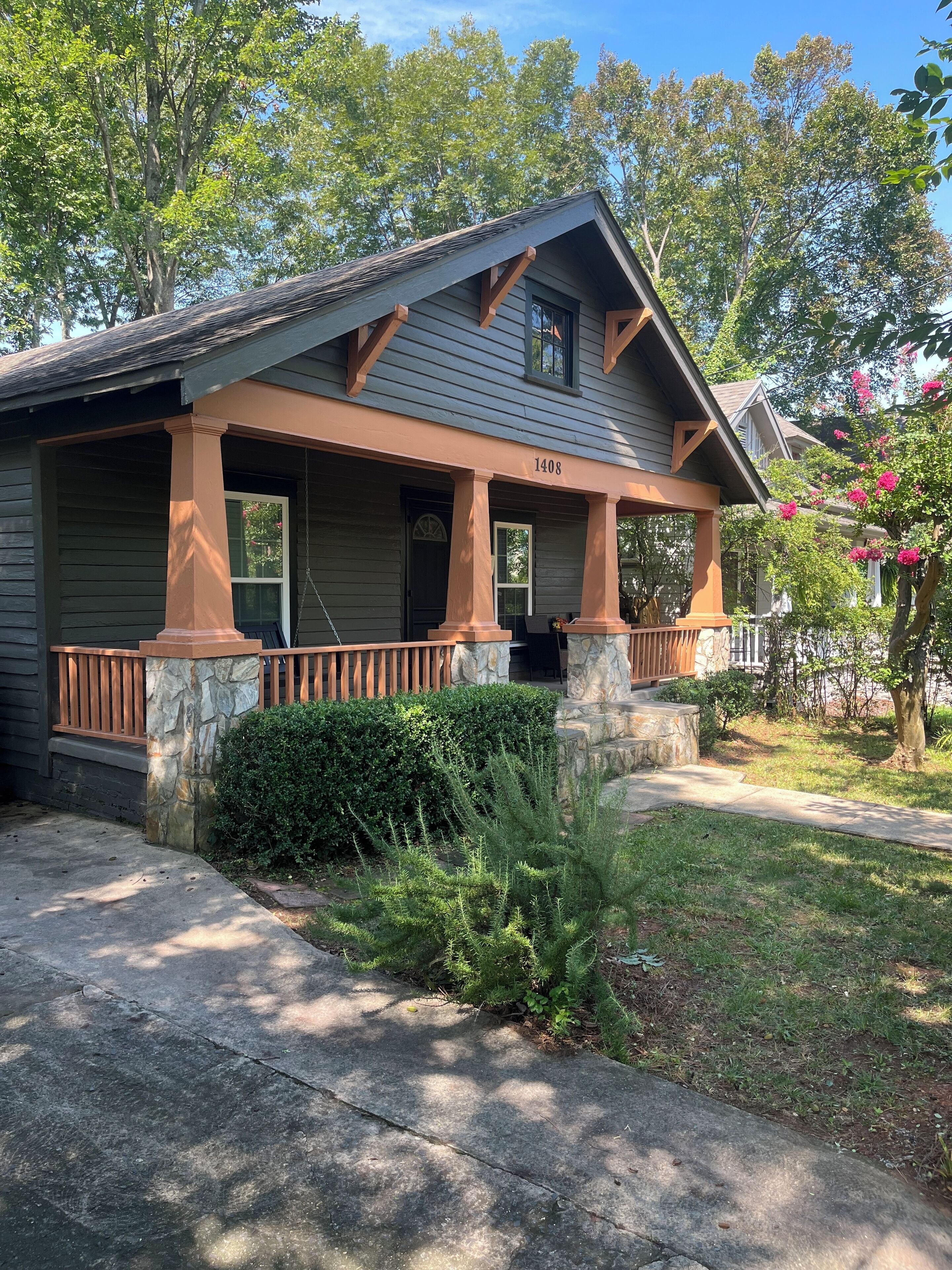 A two-story house with a porch, stone pillars, and a stone foundation.