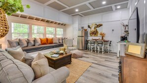 A spacious living room with a large sofa, a coffee table, and a dining area with chairs and a table. - Romantic Couples Cottage, Large Covered Deck with Hot Tub, TV,  Couches, Firepit (Clarkesville)
