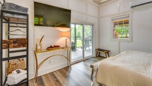 A bedroom with a bed, a ceiling fan, a window with blinds, a wooden floor, and a wall-mounted TV. - Romantic Couples Cottage, Large Covered Deck with Hot Tub, TV,  Couches, Firepit (Clarkesville)