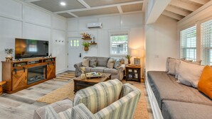 A living room with a sofa, a television, a wooden cabinet, and a fireplace. - Romantic Couples Cottage, Large Covered Deck with Hot Tub, TV,  Couches, Firepit (Clarkesville)