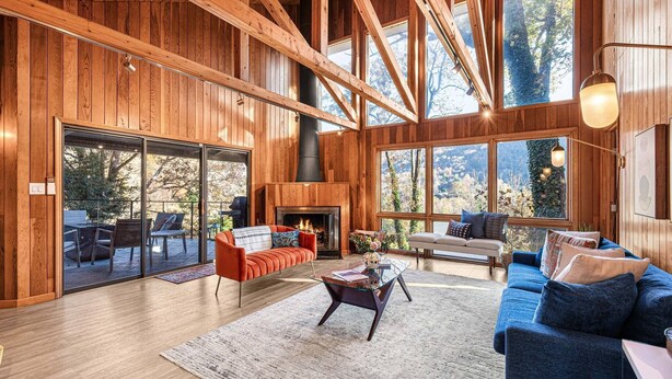 Amplia sala de estar con chimenea, ventanas grandes y vigas de madera.