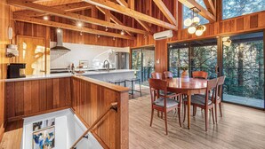 Un interior de madera con comedor, cocina y ventanas amplias.