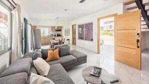 Un salon moderne avec un canapé gris, une petite table ronde et un ventilateur de plafond.