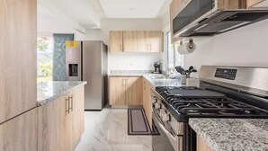 Une cuisine moderne avec des meubles en bois, une cuisinière en acier inoxydable et un four encastré.