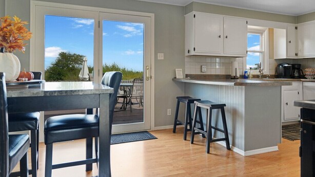 A modern kitchen with a large island, white cabinets, and a sliding glass door leading to a patio.