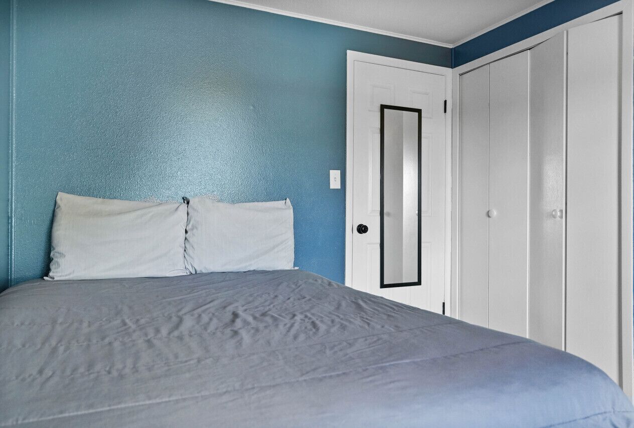 A bedroom with a bed, a door, and a wardrobe.