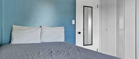 A bedroom with a bed, a door, and a wardrobe.