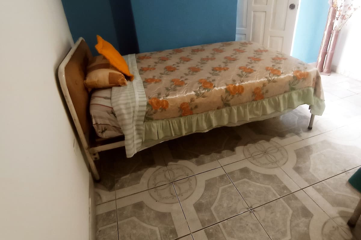 A bedroom with a bed, a door, and patterned floor tiles.