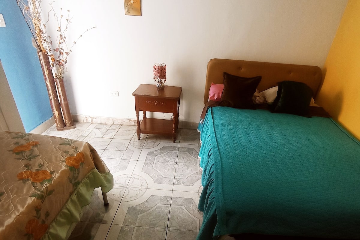 A bedroom with a bed, a nightstand, and a small table.