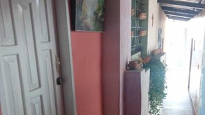 A hallway with a white door, a painting on the wall, and a staircase leading to a balcony with plants. - HOTEL EL PANECILLO (Quito)