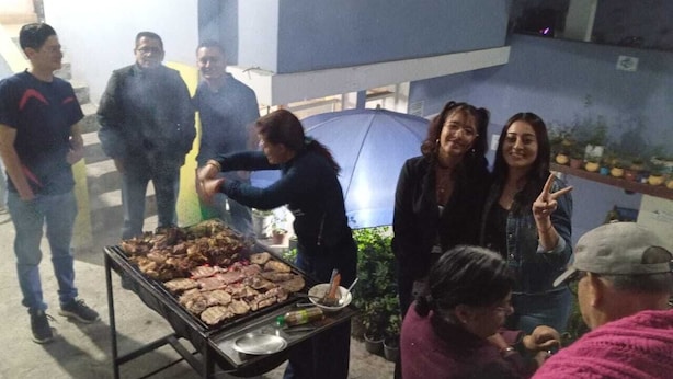 A group of people gathered around a barbecue grill outdoors. - HOTEL EL PANECILLO (Quito)
