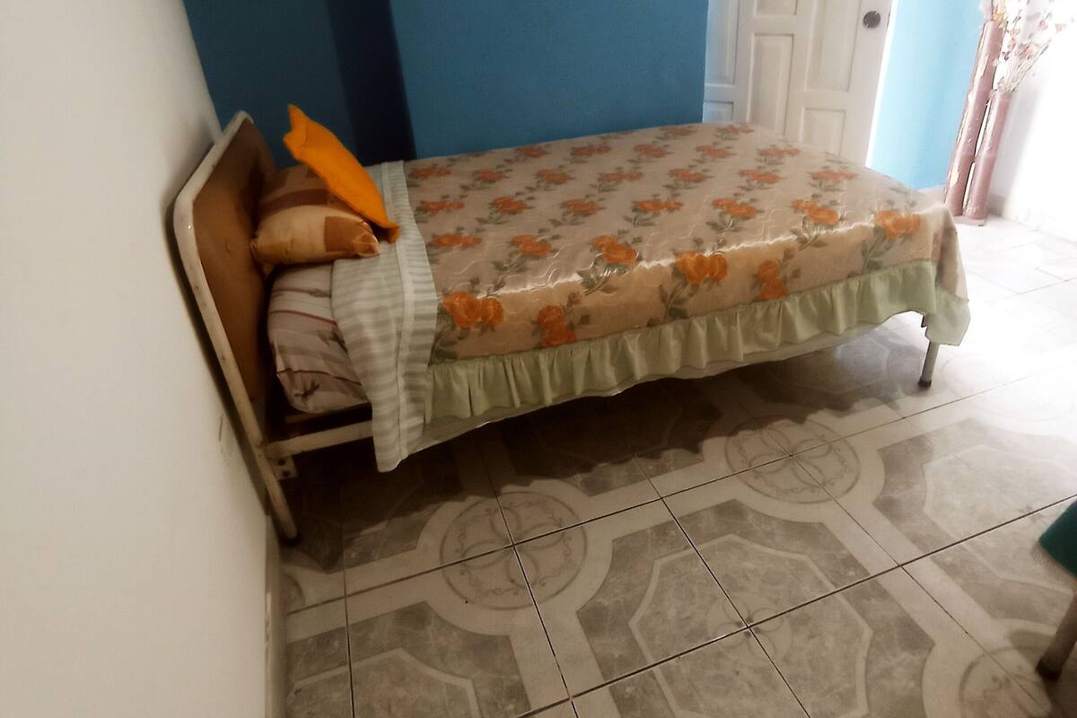 A bedroom with a bed, a door, and patterned floor tiles.