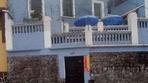 A hotel with a stone facade, a blue exterior, and a gated entrance. - HOTEL EL PANECILLO (Quito)