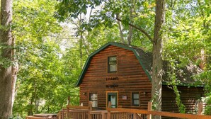 A rustic log cabin named 'ETHANS RETREAT' surrounded by trees.