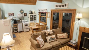A cozy living room with a sofa, a coffee table, a fireplace, and a dining area with a table and chairs.