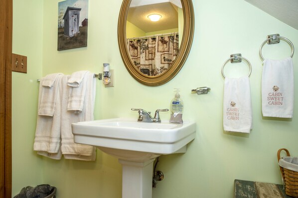 A bathroom with a white sink, a mirror, and two towels hanging on towel rings.