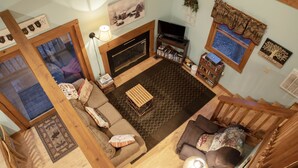 A cozy living room with a fireplace, a television, and a bookshelf.