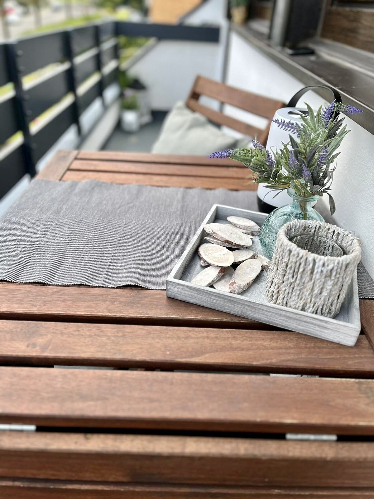 Une table en bois sur laquelle se trouve un plateau avec des aliments coupés en tranches, un panier en osier et un petit vase contenant de la lavande.