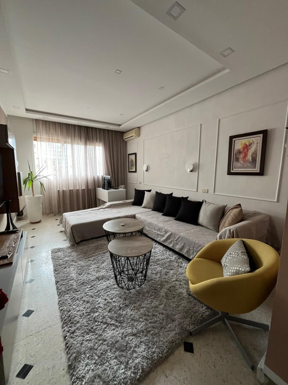 A modern living room with a sectional sofa, a round coffee table, and a yellow armchair.