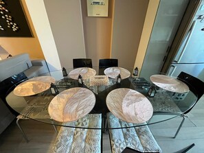 Un moderno comedor con una mesa de vidrio rodeada de sillas, un sofá y un elemento decorativo en la pared.