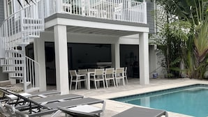 A two-story house with a balcony, a pool, and outdoor furniture. - Prime Holmes Beach Location | Heated Pool | Walk to the Beach (Holmes Beach)