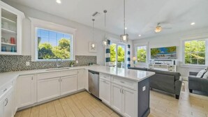 A modern kitchen with white cabinetry, a central island, and pendant lighting. - Prime Holmes Beach Location | Heated Pool | Walk to the Beach (Holmes Beach)