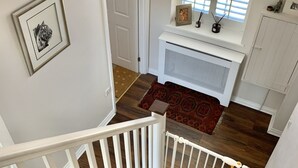 A staircase with white railings and wooden steps, leading to a room with a white radiator, a window with blinds, and a framed picture on the wall. - Historic family house near Longleat (Warminster)