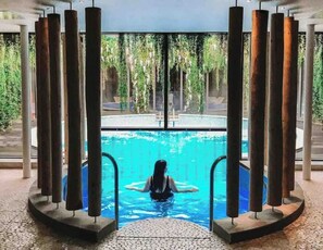 Una persona in piscina con vista su un giardino e una zona a bordo piscina.