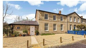 A two-story stone building with a traditional design, featuring a small attached structure with a round window and a door. - Historic family house near Longleat (Warminster)