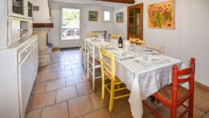 A dining area with a table set for four, chairs, a kitchen area with cabinets, and a door leading outside. - A peaceful house in Provence with a pool, located between the Luberon, Avignon, and Mont Ventoux (Monteux)