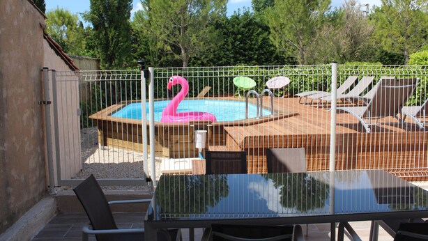 A backyard with a wooden deck, a swimming pool, lounge chairs, and a pink flamingo float. - A peaceful house in Provence with a pool, located between the Luberon, Avignon, and Mont Ventoux (Monteux)