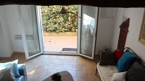 A room with a sliding glass door leading to a patio, a sofa, a coffee table, and a wall-mounted sculpture. - A peaceful house in Provence with a pool, located between the Luberon, Avignon, and Mont Ventoux (Monteux)